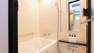 A modern bathroom with a bathtub, a handheld showerhead, a towel rack, and a mirror.