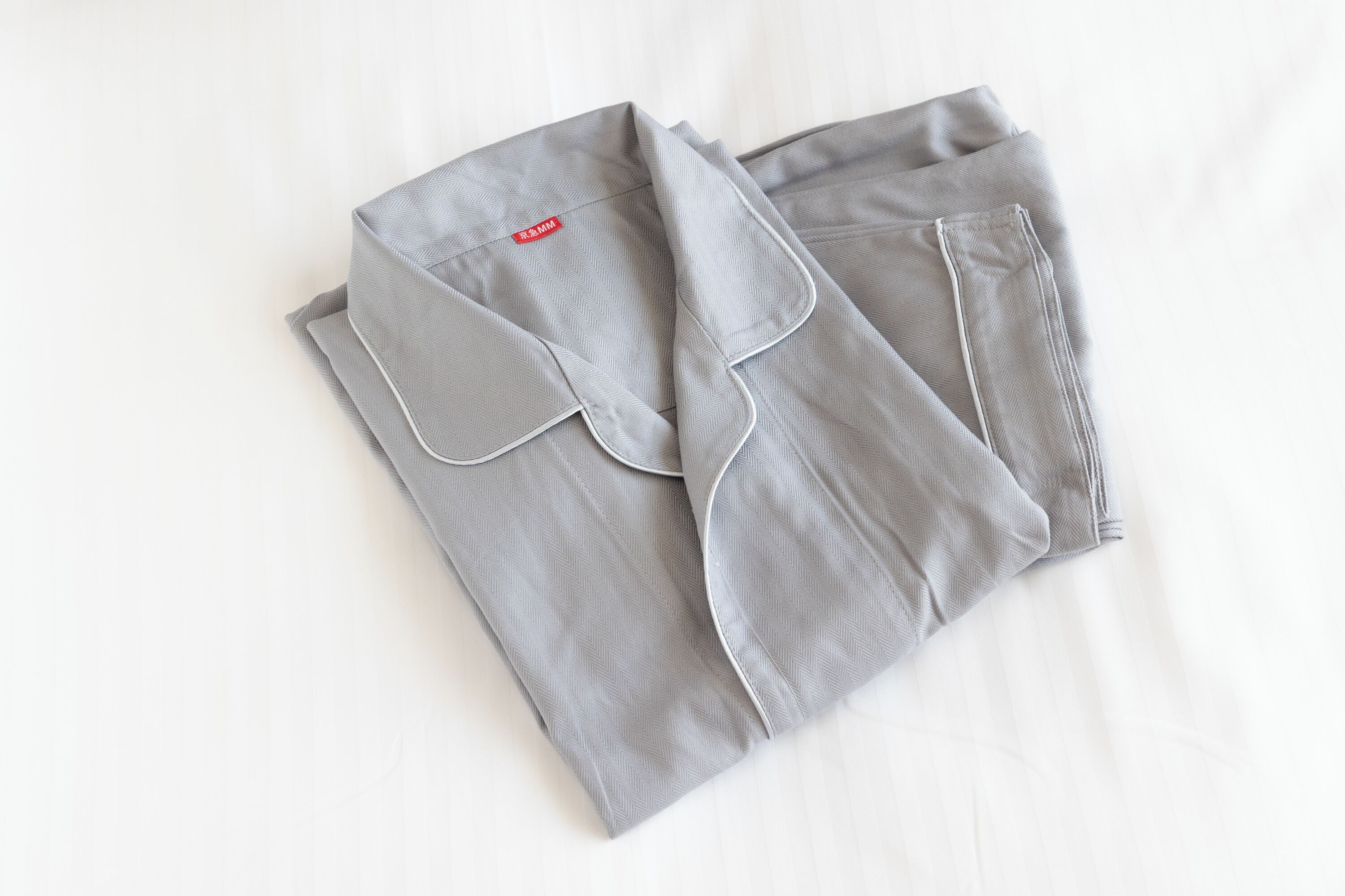 A neatly folded grey shirt with a collar and a small red tag on the left side.