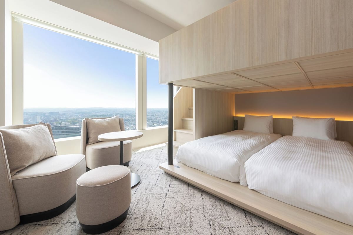 Une chambre d’hôtel moderne dotée d’un grand lit, d’un coin salon avec une table et offrant une vue sur la ville.