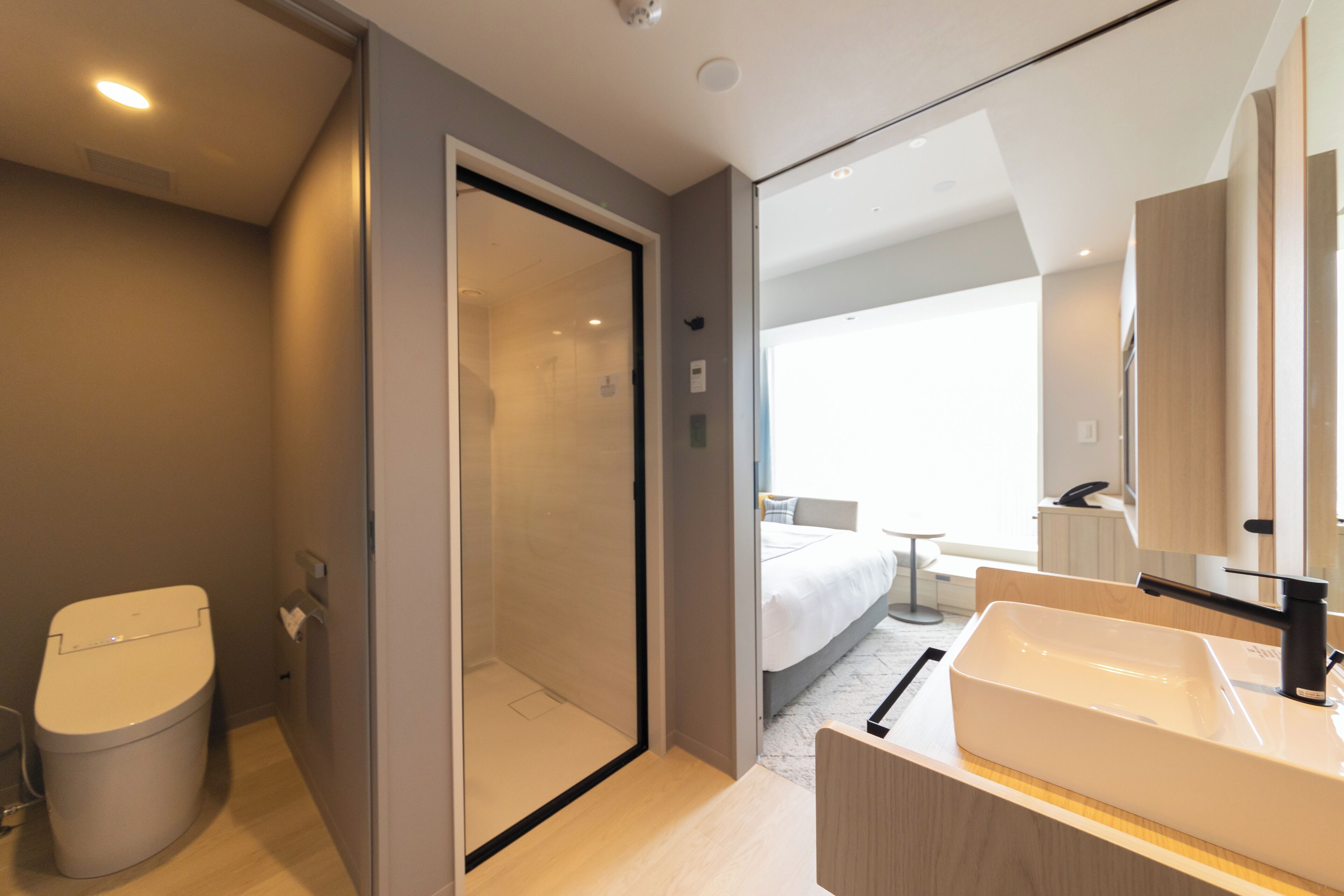 A modern bathroom with a toilet, shower, and sink.