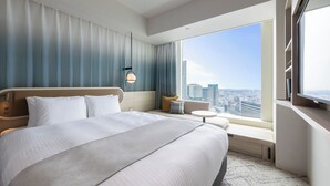 A hotel room with a large bed, a small table, a sofa, and a city view. - KEIKYU EX HOTEL MINATOMIRAI YOKOHAMA (Yokohama)