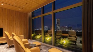 A modern lounge with leather chairs and a small table, large windows with a city view, and a wooden ceiling. - KEIKYU EX HOTEL MINATOMIRAI YOKOHAMA (Yokohama)