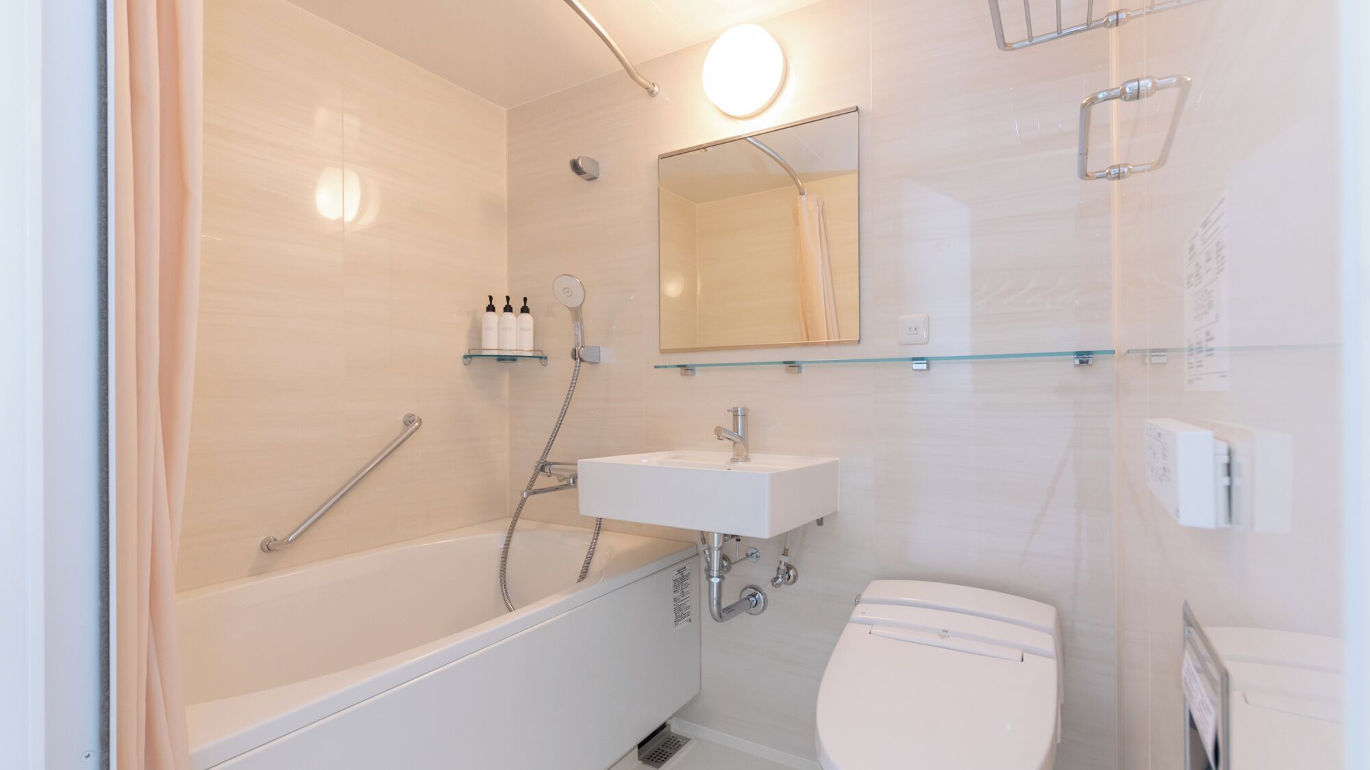 A modern bathroom with a bathtub, a sink, a toilet, and a glass shelf with toiletries.