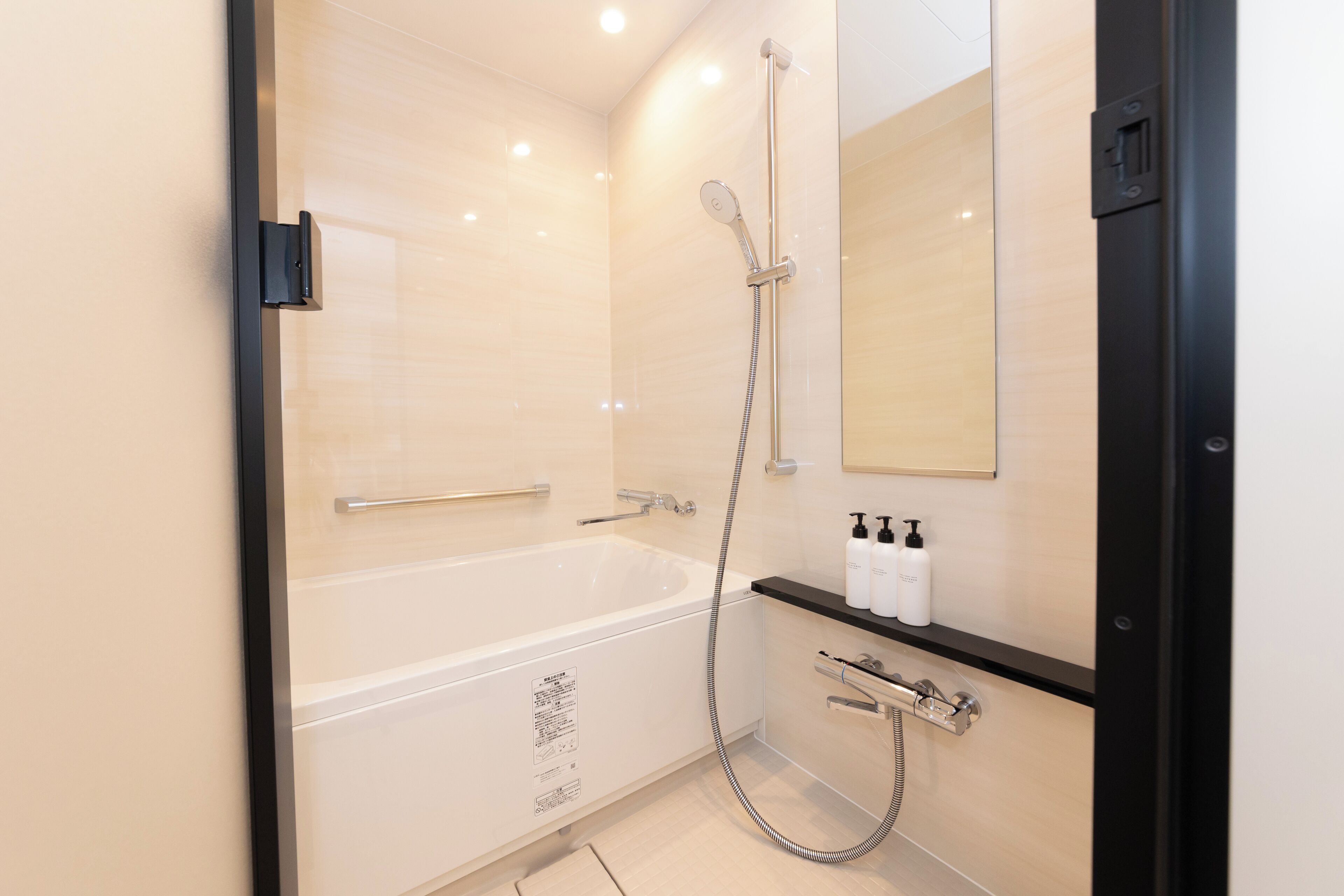 Un baño moderno con una bañera blanca, un cabezal de ducha de mano y un espejo montado en la pared.