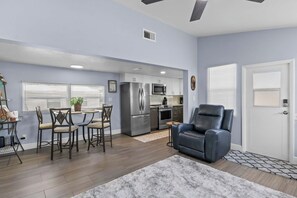 A modern living room with a grey leather sofa, a dining area with a table and chairs, and a kitchen with stainless steel appliances. - 3713 115th St.Ct.W. - Mobile home Bradenton - 2 Bedroom/ 2 Bath , maximum occupancy of 4 people. Distance to the Beach: 5 min by car. (Bradenton)
