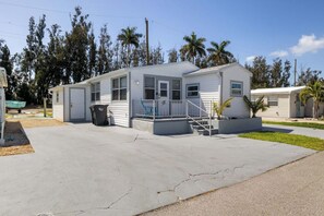 Ein Bungalow mit Veranda, Mülleimer und kleinem Garten.
