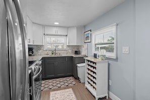 A compact kitchen with dark cabinets, a stainless steel refrigerator, a coffee maker, and a wine rack. - 3713 115th St.Ct.W. - Mobile home Bradenton - 2 Bedroom/ 2 Bath , maximum occupancy of 4 people. Distance to the Beach: 5 min by car. (Bradenton)