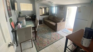 A compact living space with a dining area, a sofa, a coffee machine, and a refrigerator.