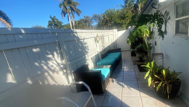 A patio area with a pool table, a green cushioned bench, and potted plants.