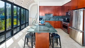 Una cocina moderna con ventanas amplias, una isla central y electrodomésticos de acero inoxidable.