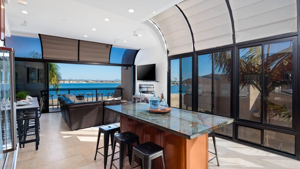 Una cocina moderna con una isla grande, taburetes de bar y vista al mar.