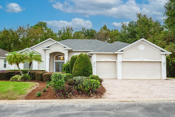 A single-story house with a garage, a well-maintained lawn, and a variety of plants. - Large 4/5 bedroom private screened pool home on quiet street not overlooked (Davenport)