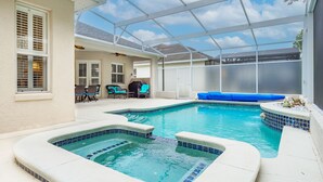Ein überdachter Pool mit Whirlpool, eine Terrasse mit Sitzgelegenheiten und Blick auf den Garten.