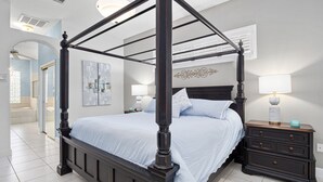 Ein Bett mit Himmel, dunkel gehalten, ein Nachttisch mit Lampe und eine Wandleuchte.