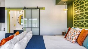 Une chambre d’hôtel moderne, dotée d’un grand lit, d’un bureau et d’une porte coulissante donnant accès à la salle de bain.