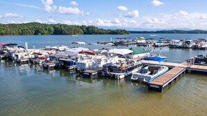 Un port de plaisance où sont amarrés différents types de bateaux, entouré d’eaux calmes et bordé d’une rive boisée.