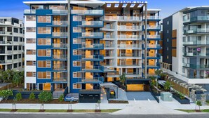 Ein mehrgeschossiges Hotel mit Balkonen, einer Dachterrasse und einem gepflegten Außenbereich mit Pflanzen.