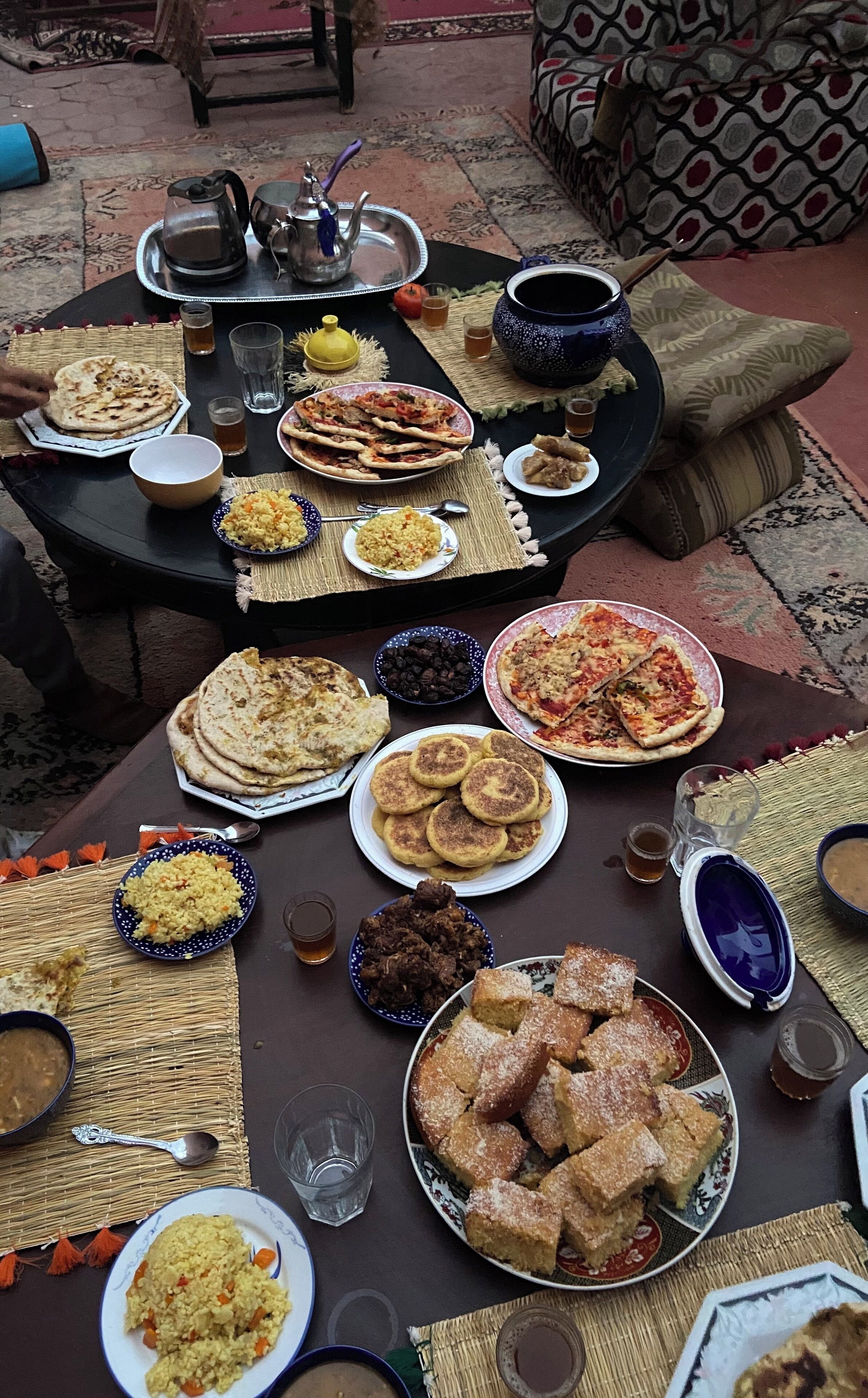 A table set with various dishes, including flatbreads, rice, and desserts, suggesting a communal meal.