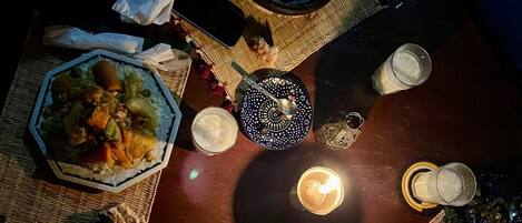 Una mesa de comedor con diversos platos y una vela, rodeada de individuales tejidos y una cesta de mimbre.