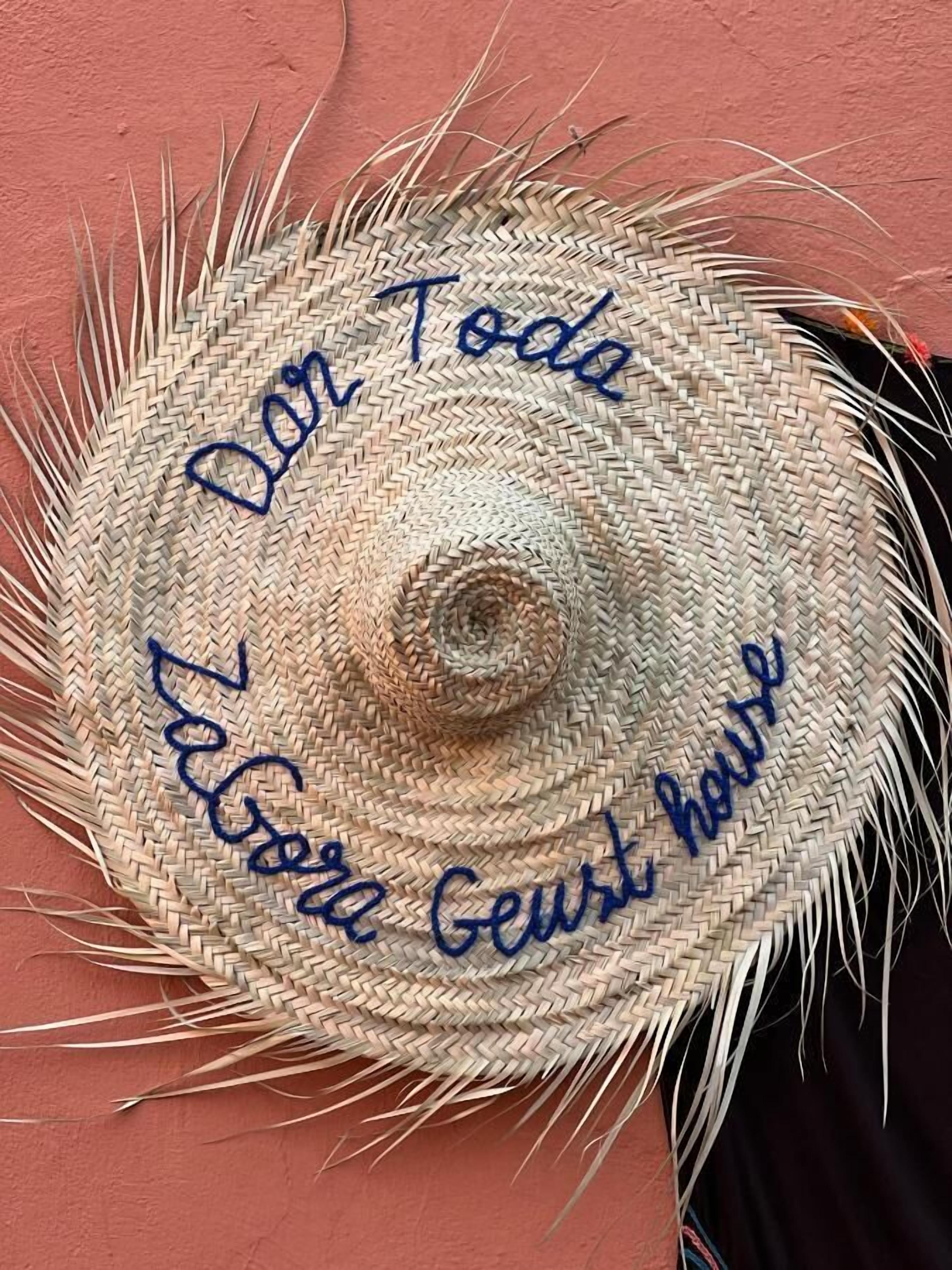 Ein Strohhut mit aufgesticktem Text.