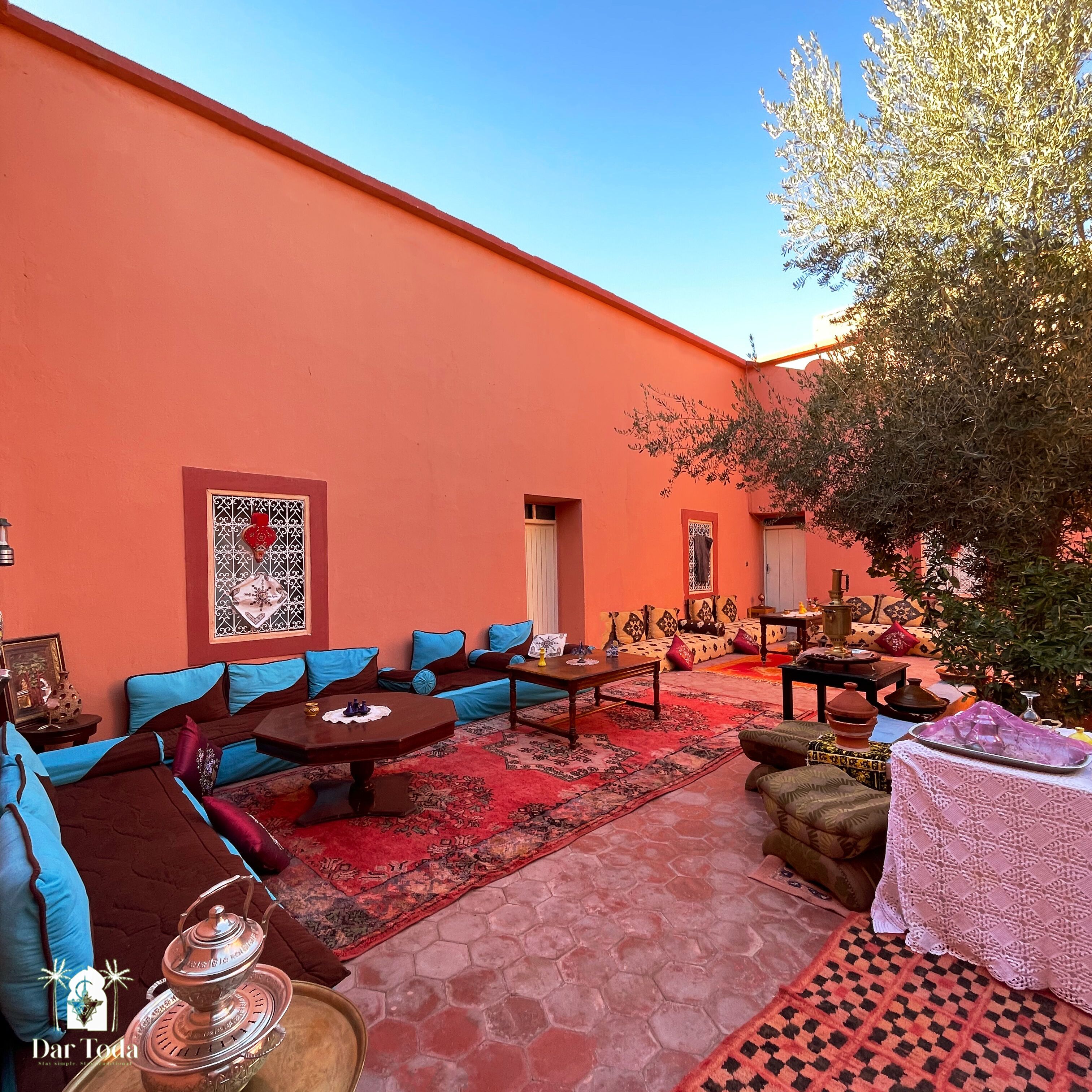 An outdoor seating area with sofas and tables, a patterned rug, and a tree.