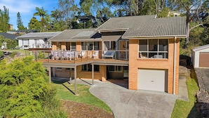 A modern two-story house with a covered patio, a garage, and a well-maintained lawn. - White Sands House by Experience Jervis Bay (Vincentia)