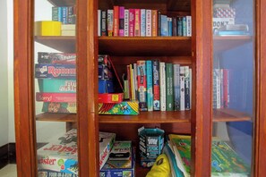 Een boekenplank met verschillende boeken en spellen, waaronder 'Rumour' en 'Sorry!'.