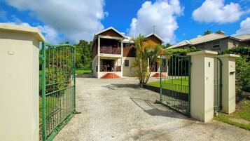 A two-story building with a gravel driveway and a green gate.