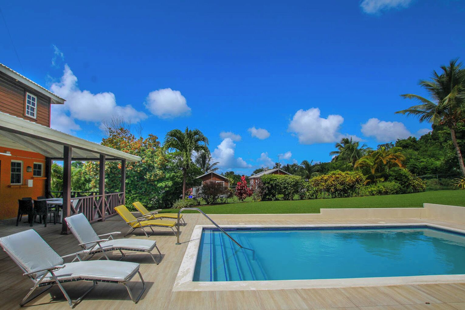 A pool area with lounge chairs and a covered patio.