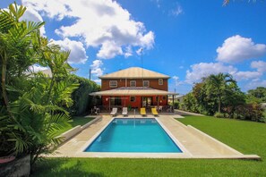 Un bâtiment à deux étages doté d’une piscine et d’un espace extérieur aménagé pour s’asseoir.
