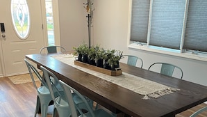 Een eetruimte met een houten tafel, lichtblauwe stoelen en potplanten.