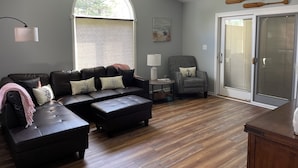 Een moderne woonkamer met een hoekbank, een kleine ronde tafel en een geruit fauteuil.