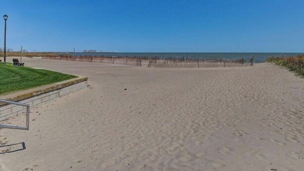 Een breed zandstrand met een helderblauwe lucht.