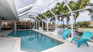 An indoor swimming pool with clear blue water, surrounded by white chairs and a glass ceiling structure. - Enjoy this lovely updated 4-bedroom, 2.5-bath waterfront home 2.5 miles from Tigertail Beach (Marco Island)