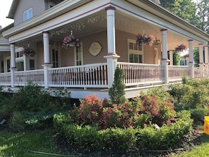 Ein zweistöckiges Haus mit einer Veranda, weißen Säulen und hängenden Blumenkörben.