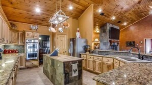 A spacious kitchen with granite countertops, wooden cabinets, and a central island. - Luxurious farm house! 5-bed, 4 bath, with pool. (Bonham)