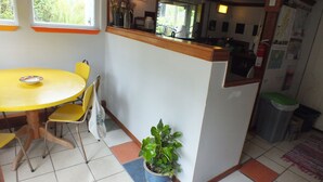 Una cocina compacta con una mesa y sillas amarillas, una planta en maceta y una pequeña barra central.