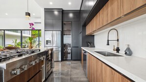 Una cocina moderna con estufa de acero inoxidable, armarios de madera, encimera blanca y lavavajillas integrado.