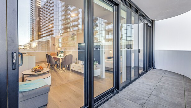 Un apartamento moderno con balcón, zona de comedor y vistas a edificios altos.