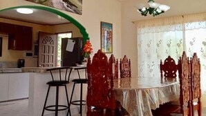 Comedor con mesa, sillas y cocina al fondo.