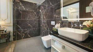Une salle de bain moderne avec un grand miroir, un lavabo blanc et un espace douche.