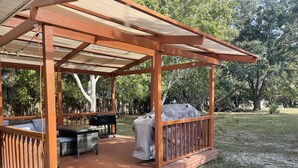 A covered outdoor seating area with a grill and a covered barbecue. - Tranquility on a Lake House- 3 miles from Weeki Wachee River  (Spring Hill)