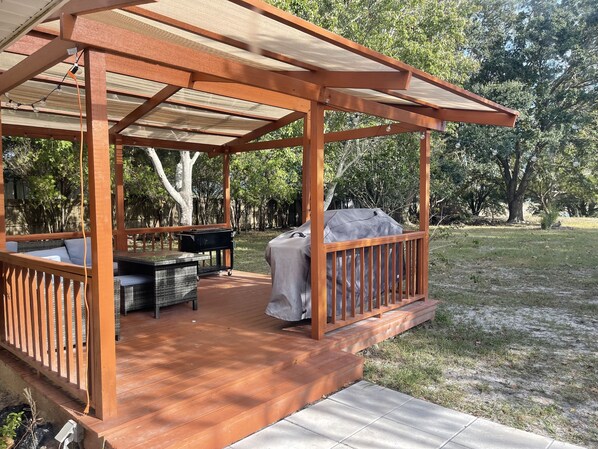 Un espacio de estar al aire libre con techo, una parrilla y un área de barbacoa cubierta.