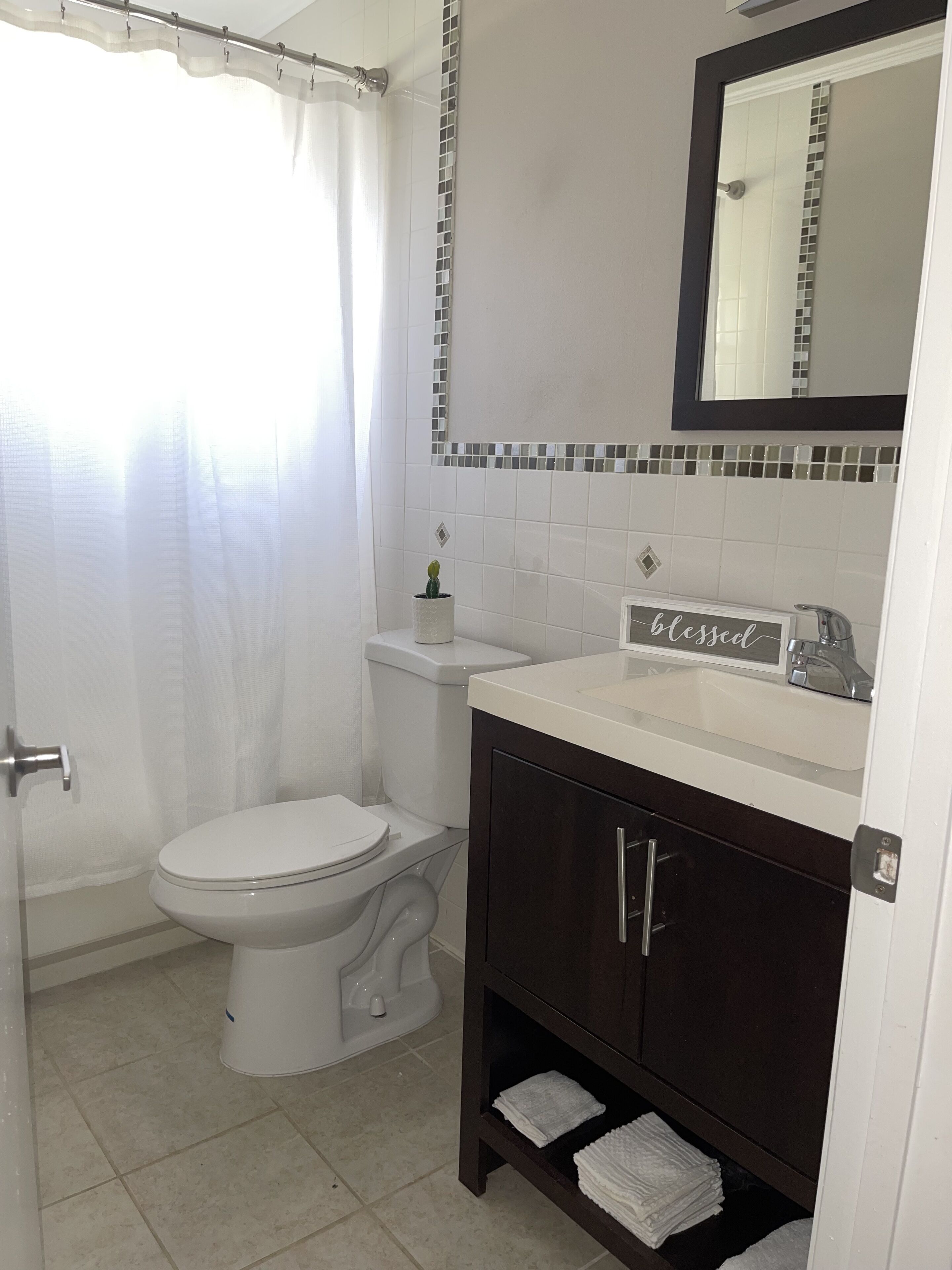 A bathroom with a toilet, sink, and mirror.
