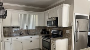 A kitchen with white cabinets, stainless steel appliances, and a granite countertop. - Tranquility on a Lake House- 3 miles from Weeki Wachee River  (Spring Hill)