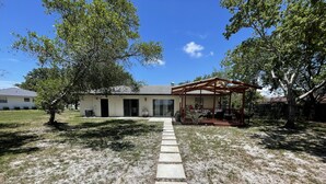 A house with a covered patio and a stone pathway leading to the entrance. - Tranquility on a Lake House- 3 miles from Weeki Wachee River  (Spring Hill)