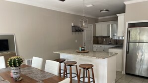 A kitchen with a central island, white cabinetry, and a stainless steel refrigerator. - Tranquility on a Lake House- 3 miles from Weeki Wachee River  (Spring Hill)