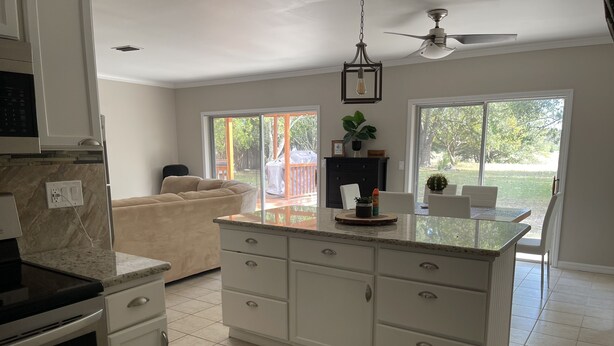 A kitchen with white cabinets, a granite countertop, a built-in oven, and a ceiling fan. - Tranquility on a Lake House- 3 miles from Weeki Wachee River  (Spring Hill)