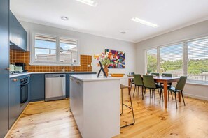Eine moderne Küche mit Kochinsel, Holzboden und Essbereich mit Stühlen und Tisch.