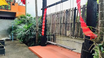 A wooden fence with red fabric decorations, a concrete floor, and green plants.
